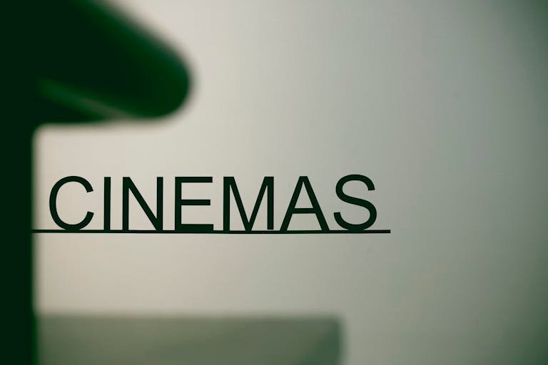 Minimalist cinema sign on pastel background, conveying a contemporary urban vibe.